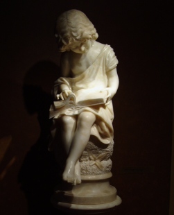 Alabaster sculpture of a child reading a book.   The origin of this sculpture is that of Italy from 1880.